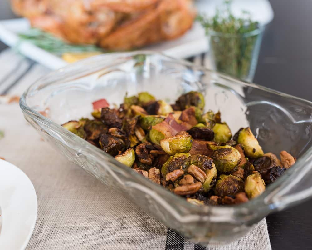 Glass dish of roasted Brussels sprouts with pecans